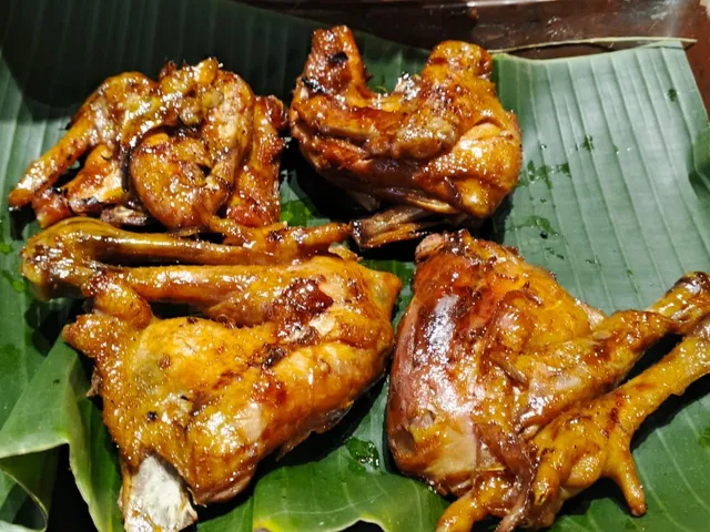 Potongan ayam bakar berbumbu di atas daun pisang