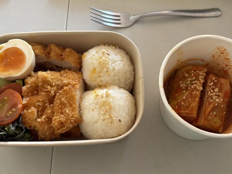 Kotak bento berisi nasi kepal, lauk, telur, dan sayur