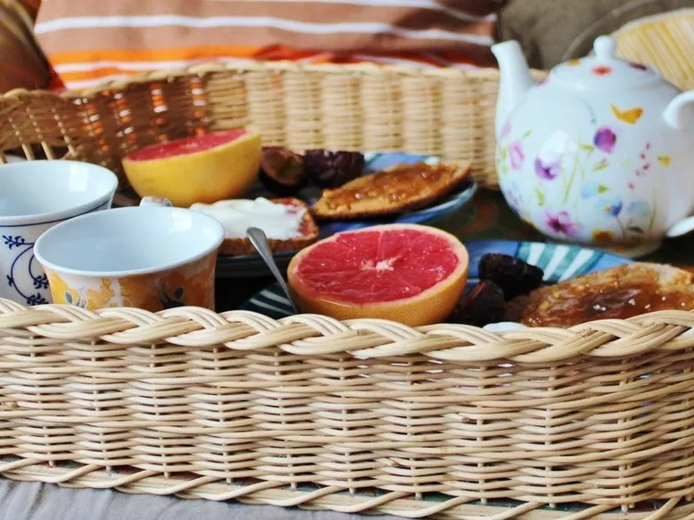 Keranjang rotan berisi kue dan peralatan minum teh